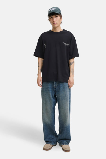 Zwart T-shirt met korte mouwen van PREMIUM by JACK & JONES, gedragen met een wijde blauwe jeans en een groene pet.