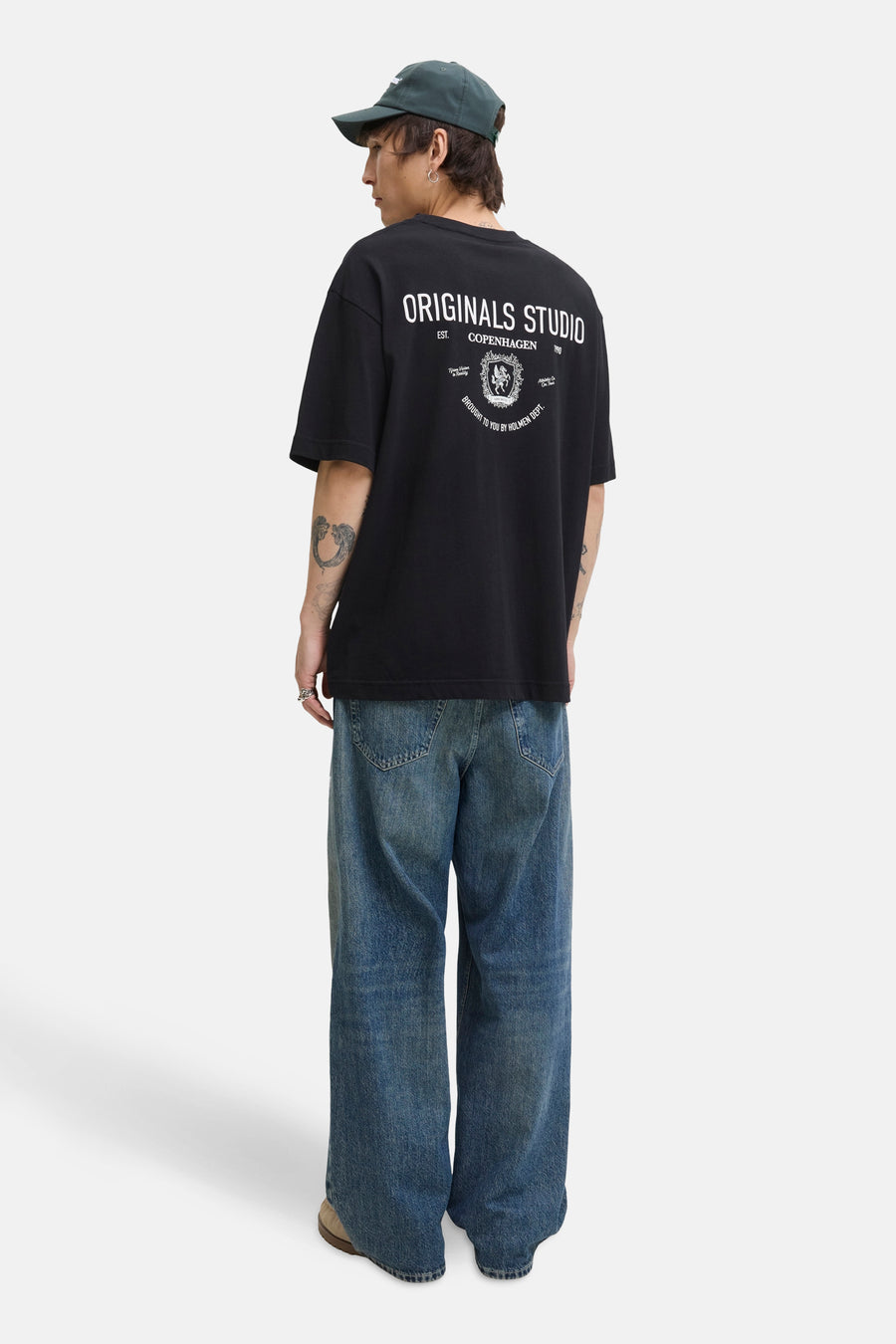 Zwart T-shirt met korte mouwen van PREMIUM by JACK & JONES, met opdruk op de rug, gedragen met een wijde jeans en een pet.