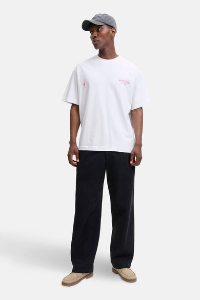 Wit T-shirt met korte mouwen van PREMIUM by JACK & JONES, met rode opdrukken, gedragen met een wijde zwarte broek en bootschoenen.