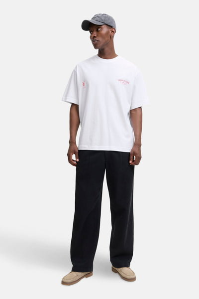 Wit T-shirt met korte mouwen van PREMIUM by JACK & JONES, met rode opdrukken, gedragen met een wijde zwarte broek en bootschoenen.