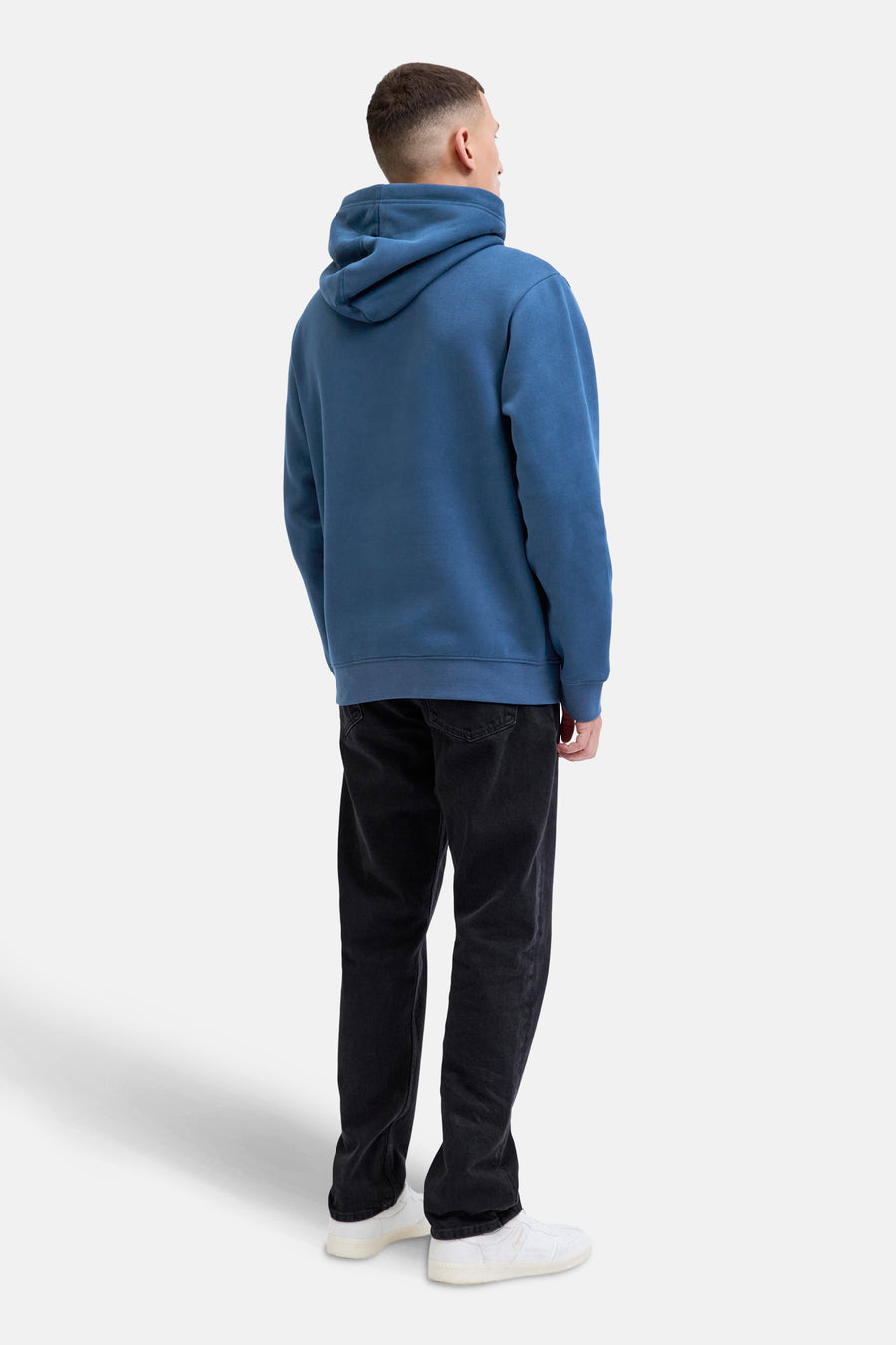 Blauwe hoodie van JACK & JONES, achterkant, gedragen met een zwarte broek en witte sneakers.