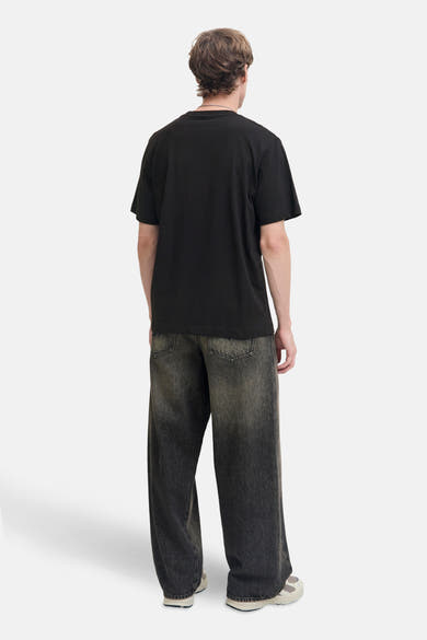 Zwart T-shirt met korte mouwen van JACK & JONES, gedragen met een wijde broek en sportschoenen.