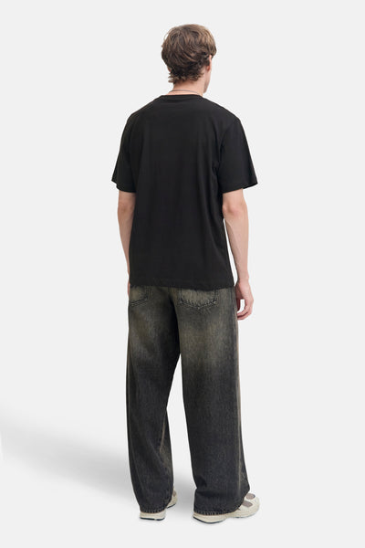 T-shirt noir à manches courtes de JACK & JONES, porté avec un pantalon ample et des chaussures de sport.