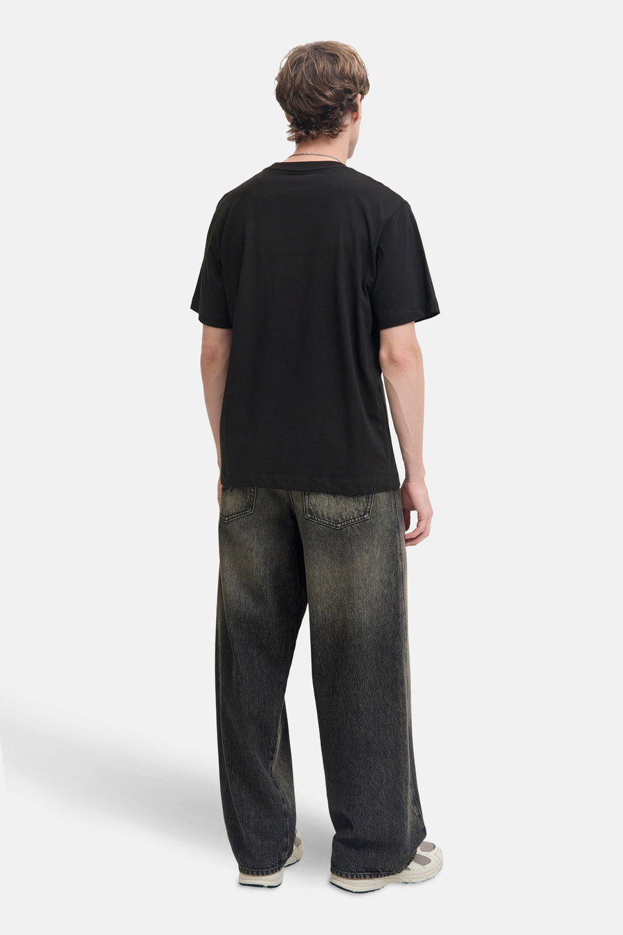 Zwart T-shirt met korte mouwen van JACK & JONES, gedragen met een wijde broek en sportschoenen.