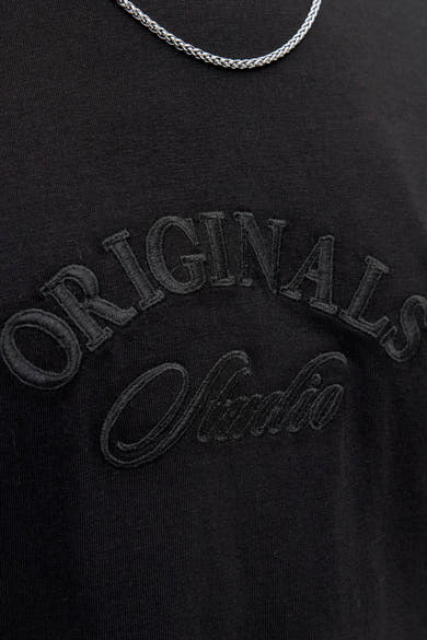 Zwart T-shirt met korte mouwen van JACK & JONES met geborduurde "Originals Studio" letters en zilveren ketting.