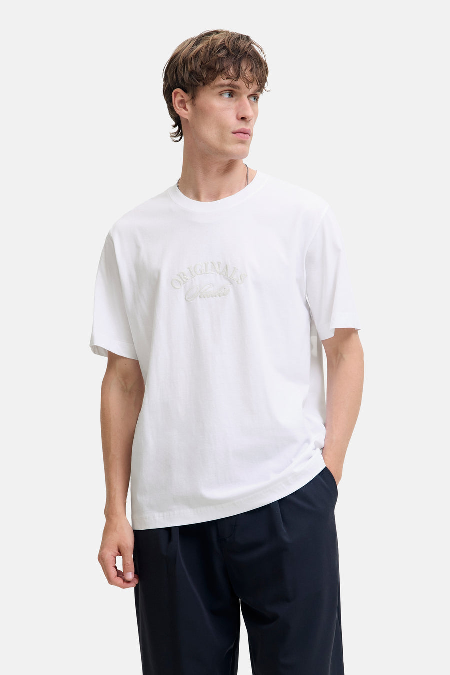 Wit T-shirt met korte mouwen van JACK & JONES, gedragen met een wijde zwarte broek en zwarte lakleren schoenen.