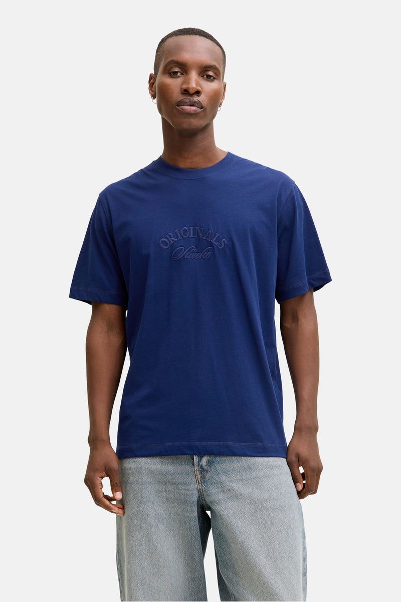 T-shirt à manches courtes bleu de JACK & JONES, avec logo brodé sur le devant, porté avec un jean clair.
