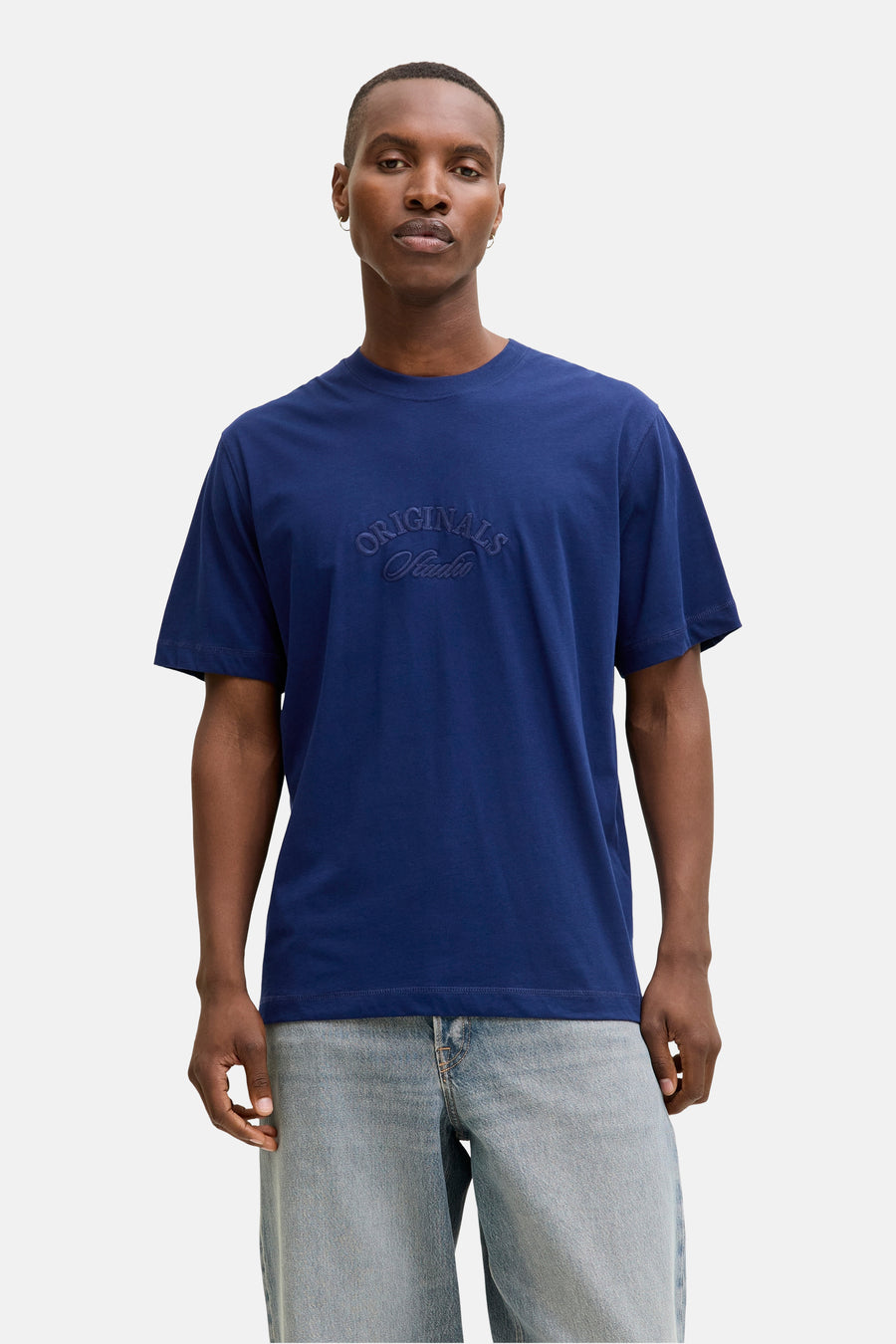 Blauw T-shirt met korte mouwen van JACK & JONES, gedragen met een geruit overhemd en een wijde jeans.