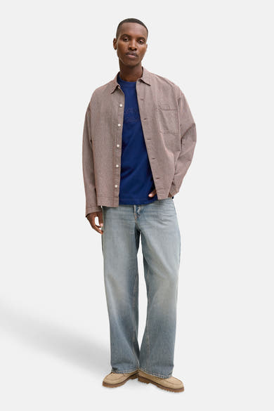 T-shirt bleu à manches courtes de JACK & JONES, porté avec une chemise à carreaux et un jean ample.