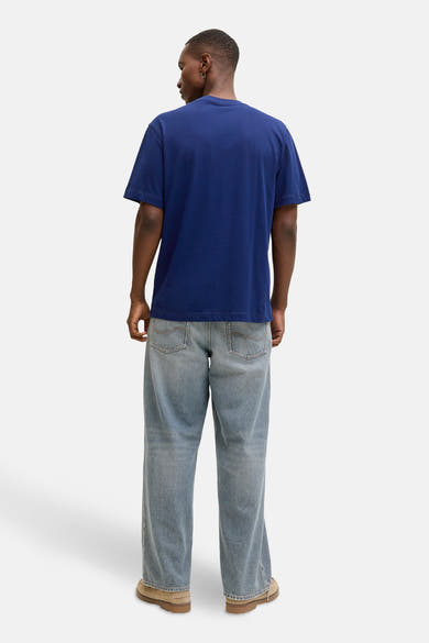 Blauw T-shirt met korte mouwen van JACK & JONES, gedragen met een wijde spijkerbroek en bruine schoenen.