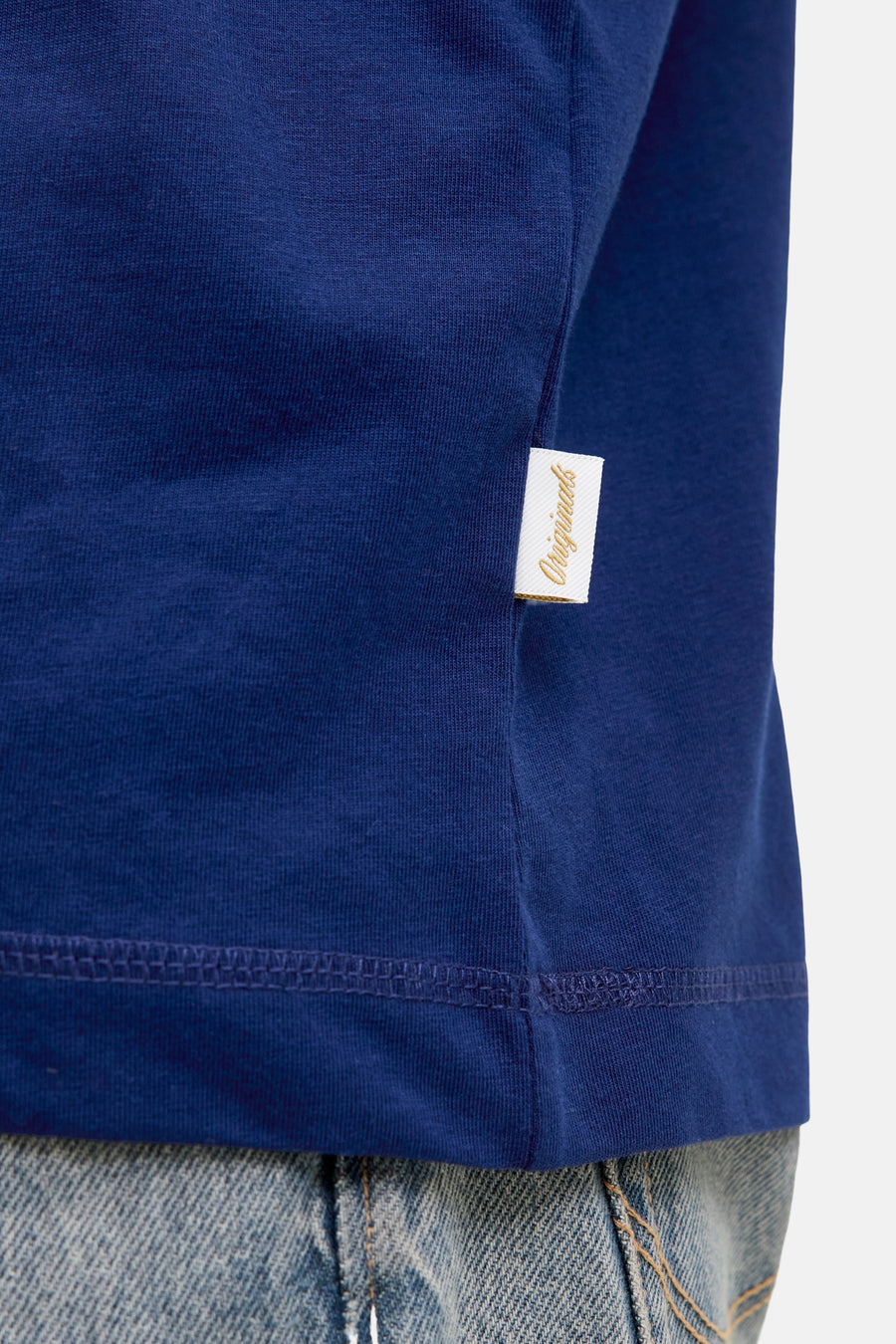 Blauw T-shirt met korte mouwen van JACK & JONES, met een gouden 'Originals'-label en gedragen met een spijkerbroek.