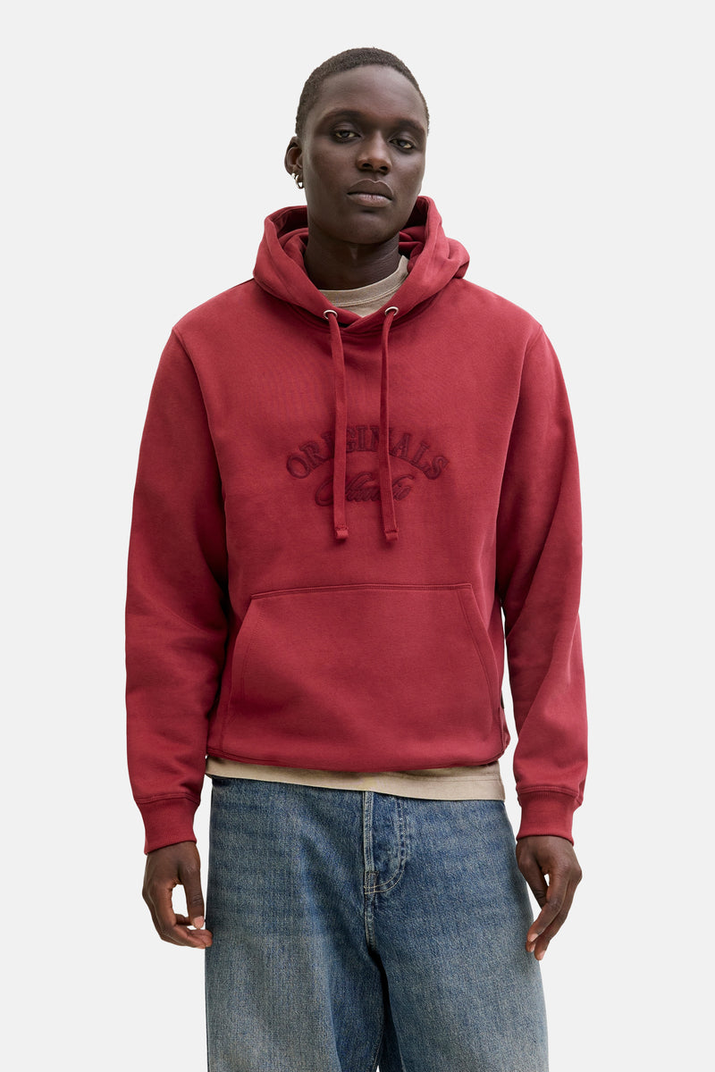 Rode hoodie Originals by Jack & Jones, gedragen met een beige jas met rits en een wijde blauwe jeans.