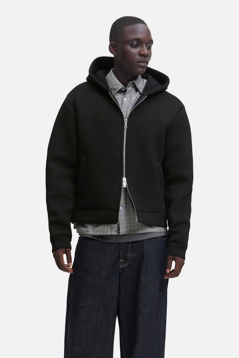 Zwarte bodywarmer van JACK & JONES, gedragen over een geruit overhemd en een wijde spijkerbroek.