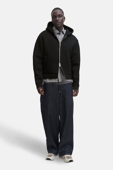 Zwarte bodywarmer JACK & JONES gedragen over een geruit overhemd en een wijde jeans.