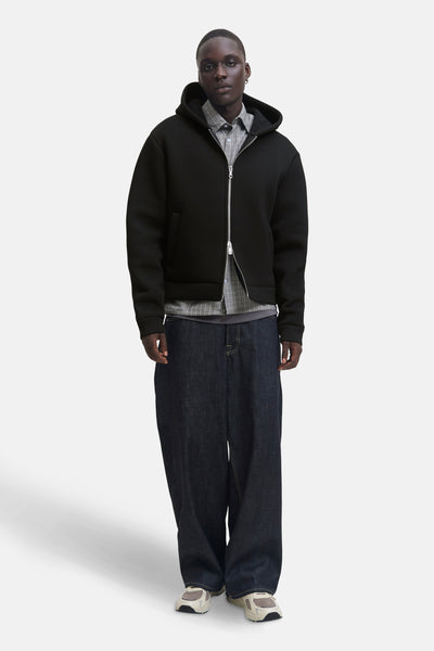 Zwarte bodywarmer JACK & JONES gedragen over een geruit overhemd en een wijde jeans.