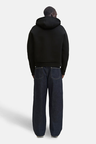 Zwarte JACK & JONES bodywarmer met capuchon, gedragen met een wijde marineblauwe jeans, achterzijde.