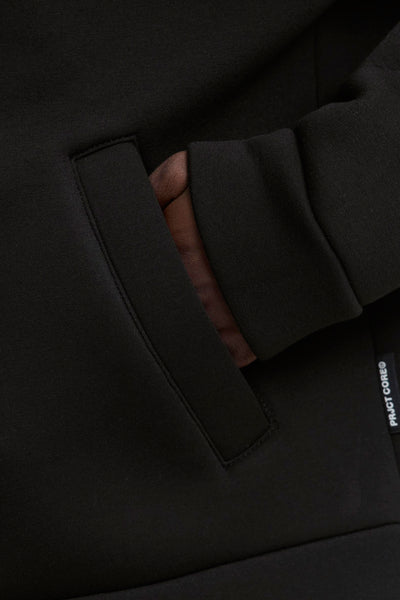 Sweat zippé noir de JACK & JONES avec une main dans la poche.