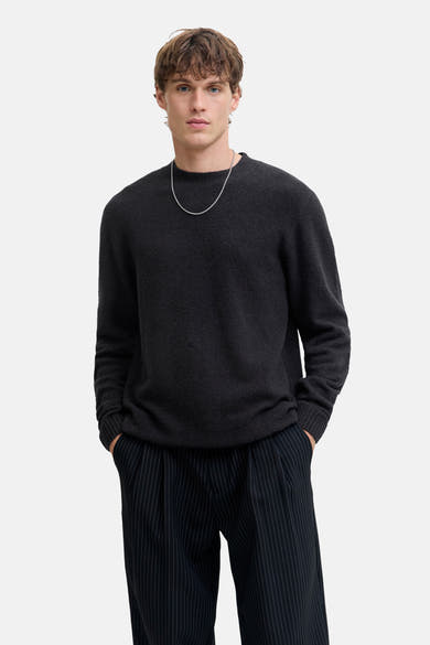 Zwart poloshirt met korte mouwen van JACK & JONES, gedragen met een zilveren ketting en een gestreepte broek.