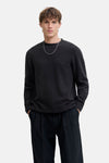 Zwart poloshirt met korte mouwen van JACK & JONES, gedragen met een zilveren ketting en een gestreepte broek.