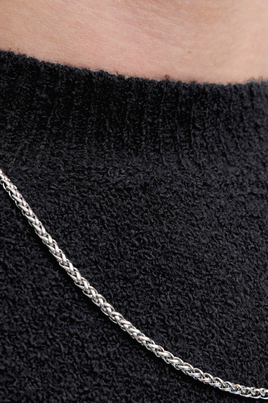 Zwart poloshirt met korte mouwen van JACK & JONES, met een getextureerde stof en een zichtbare zilveren ketting.