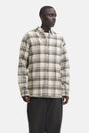 Chemise à manches longues beige de JACK & JONES, à carreaux marron et noirs, portée avec un t-shirt blanc et un pantalon foncé.