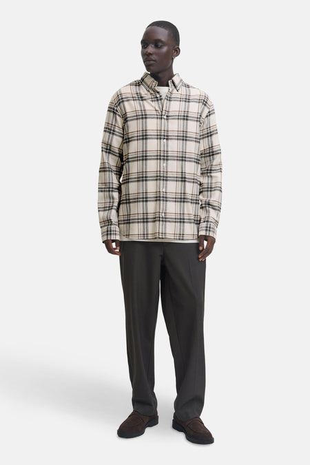 Chemise à manches longues beige à carreaux par JACK & JONES, portée avec un t-shirt blanc et un pantalon foncé.
