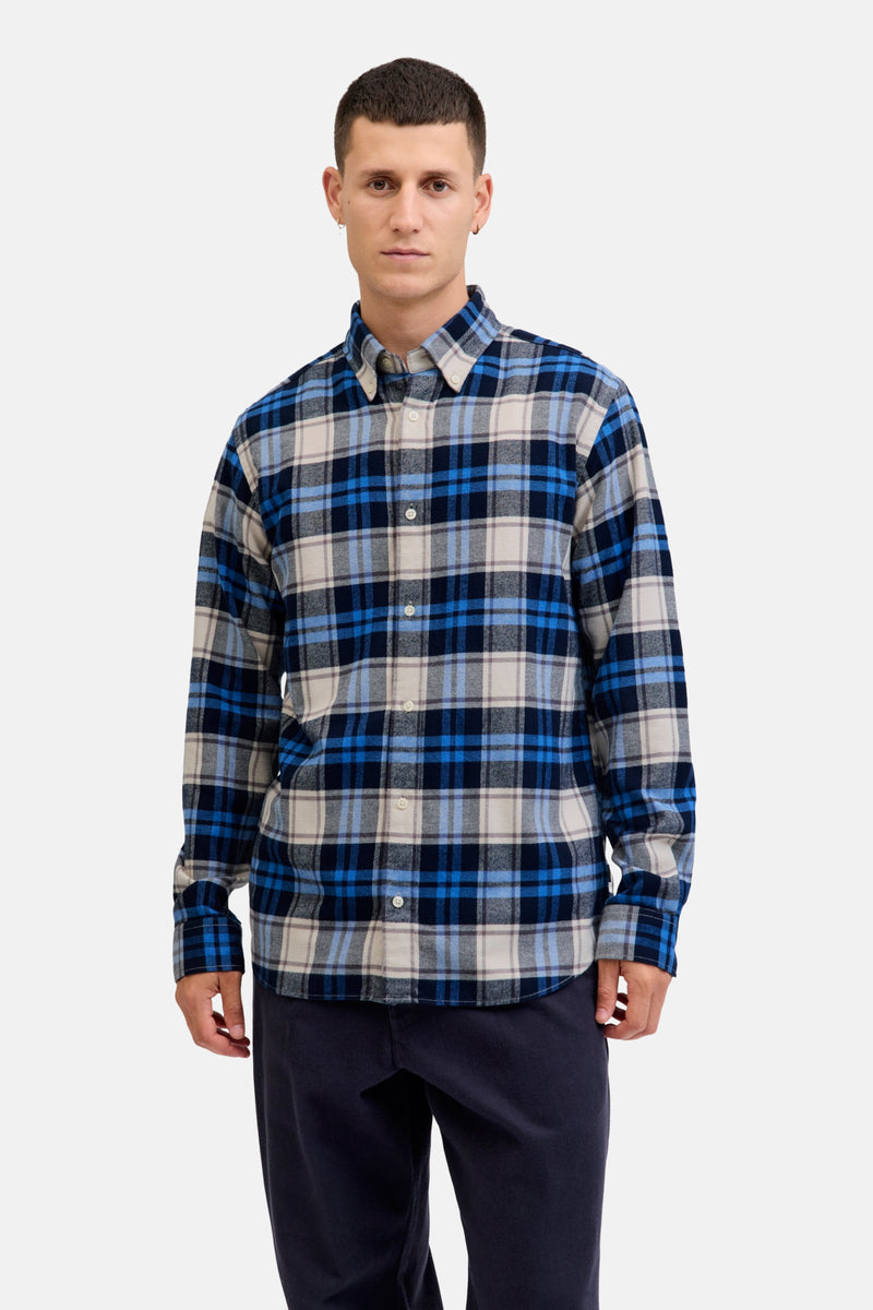 Chemise à manches longues bleue à carreaux, par JACK & JONES, portée avec un pantalon bleu marine.