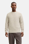 Ronde hals trui met kabelsteek van JACK & JONES, gedragen met een camelkleurige jas en een grijze broek.
