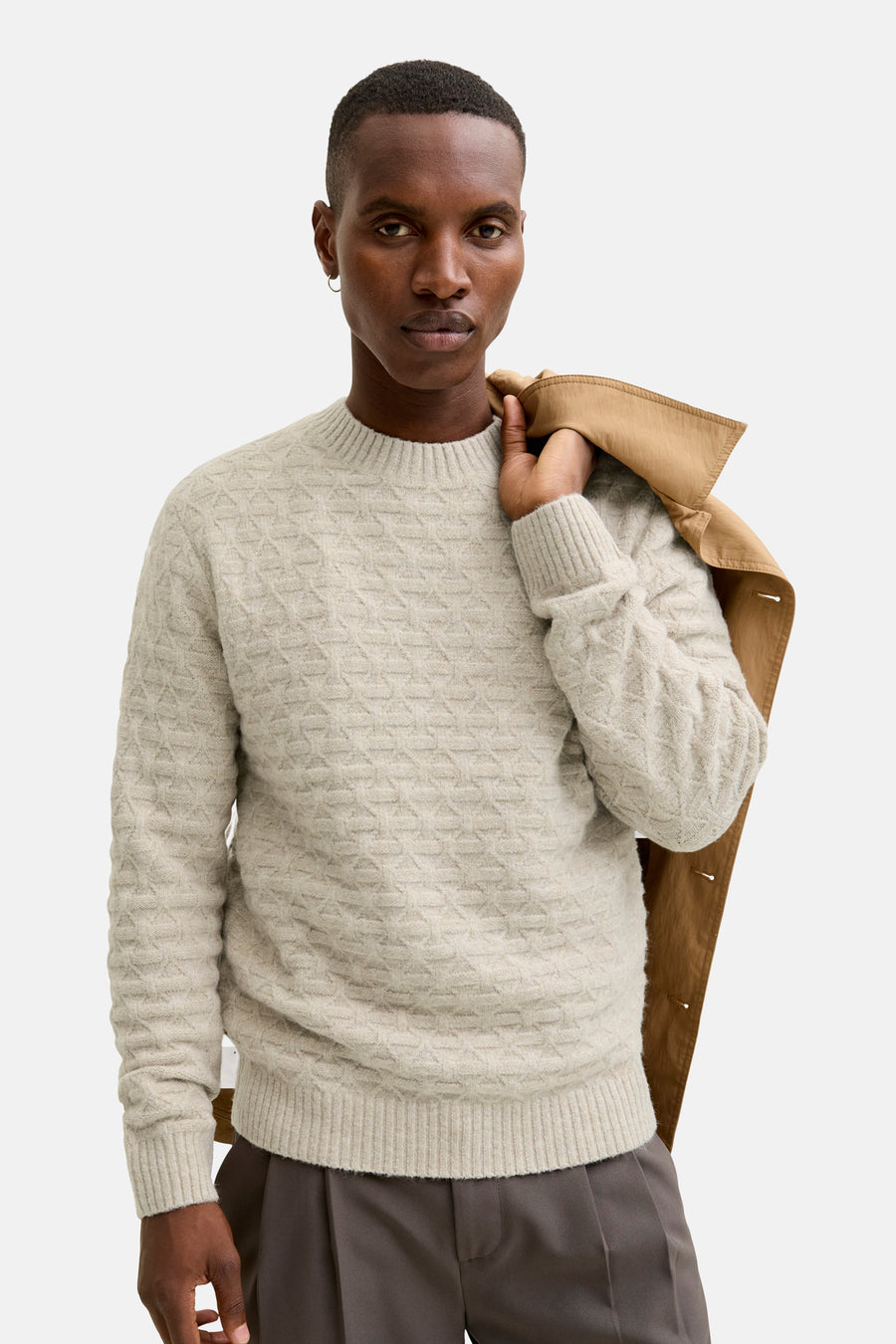 Ronde hals trui grijs gemêleerd van JACK & JONES, met subtiel textuurpatroon, gedragen met een grijze broek en een bruin jasje over de schouder.