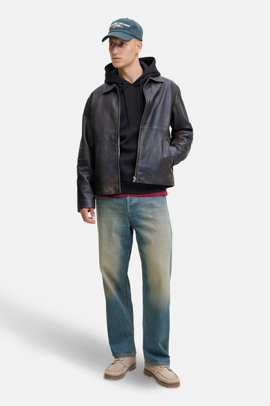 Zwarte hoodie van JACK & JONES, gedragen met een leren jas en een verbleekte spijkerbroek.