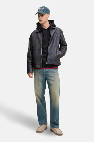 Zwarte hoodie van JACK & JONES, gedragen met een leren jas en een verbleekte spijkerbroek.