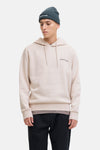 Beige hoodie van JACK & JONES, gedragen met een donkergroene muts, een zwarte broek en beige schoenen.
