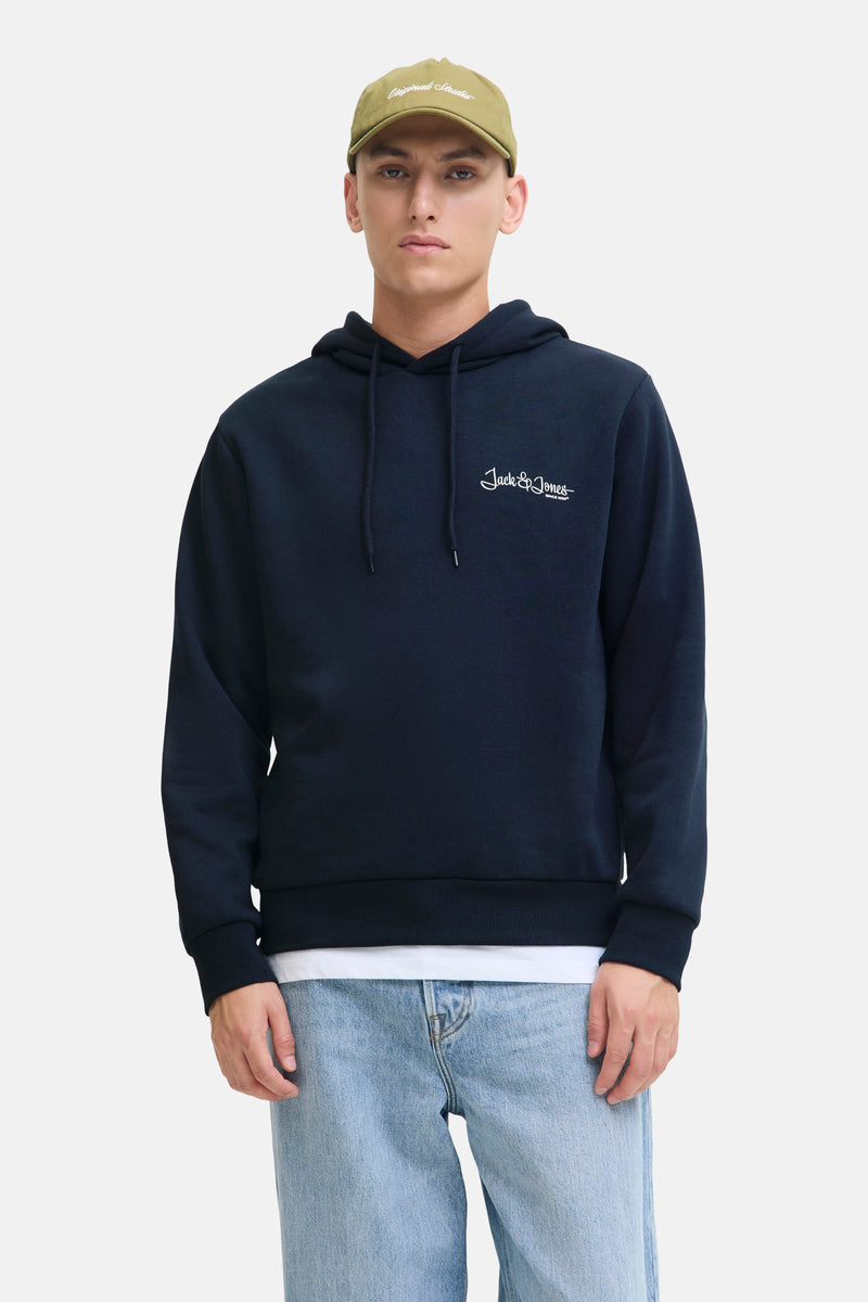 Marineblauwe hoodie van JACK & JONES, gedragen met een lichtblauwe wijde jeans en een kaki pet.