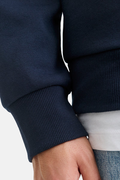 Blauwe sweater van JACK & JONES, getextureerd detail op de nauwsluitende mouw, gedragen met een wit T-shirt.