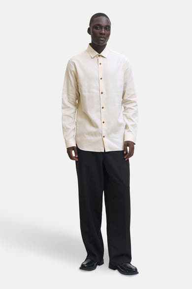 Chemise à manches longues beige de PREMIUM by JACK & JONES, avec boutons marron et pantalon noir ample.
