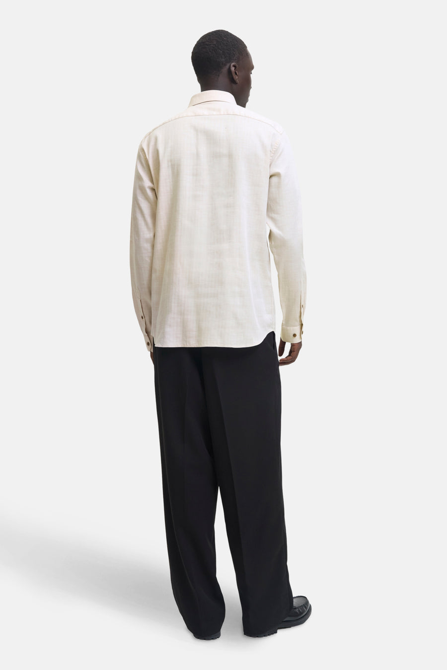 Chemise beige à manches longues de PREMIUM by JACK & JONES, portée avec un pantalon noir ample et des chaussures.