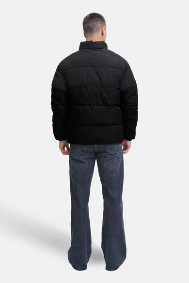 Kort zwart jack van JACK & JONES, van achteren gezien, gedragen met een verbleekte spijkerbroek.