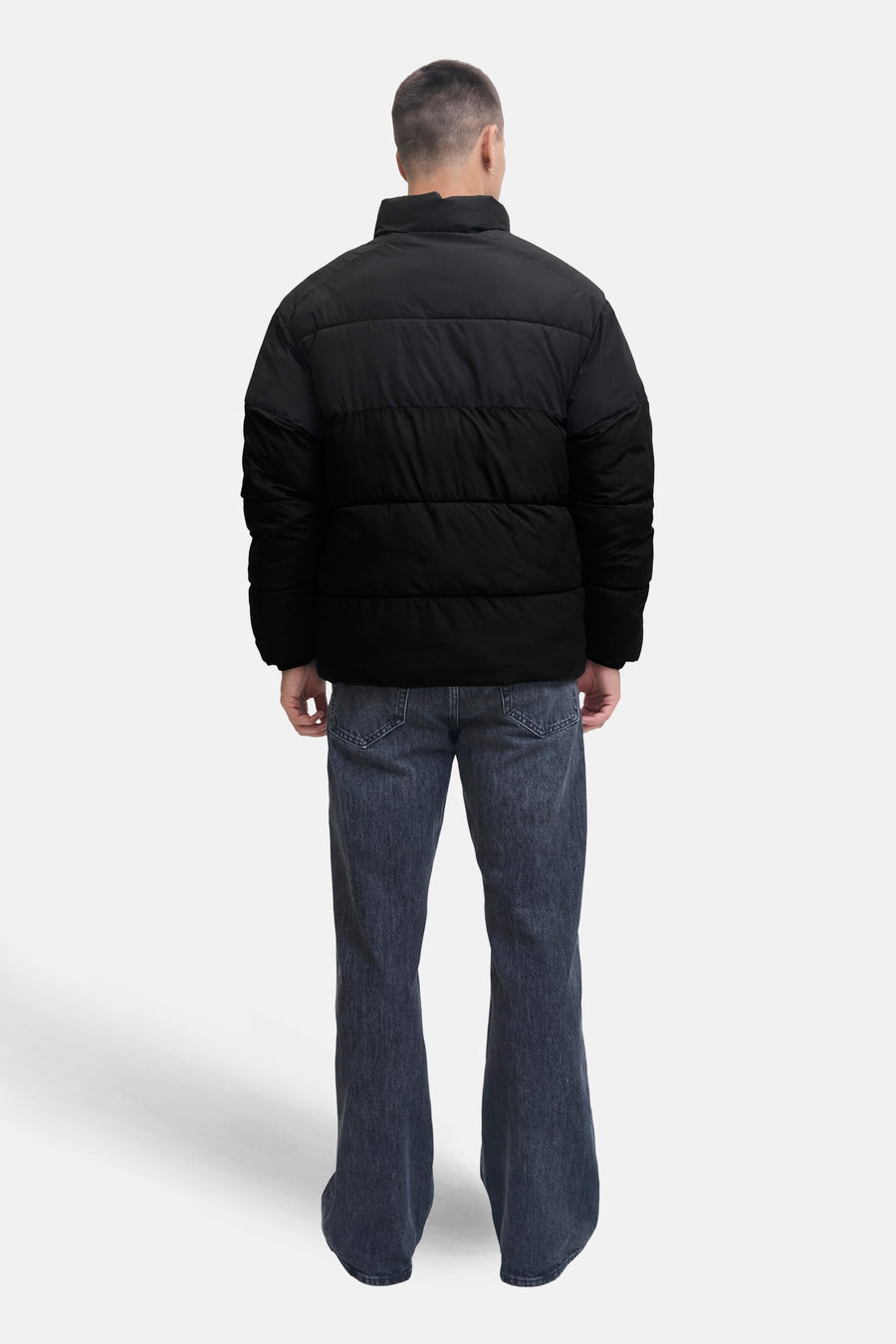 Kort zwart jack van JACK & JONES, van achteren gezien, gedragen met een verbleekte spijkerbroek.