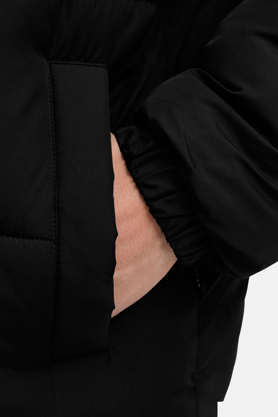 Korte zwarte jas van JACK & JONES met een hand in de zak.