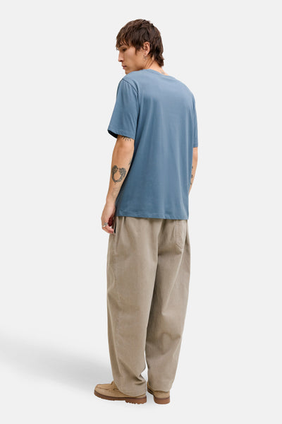 Blauw T-shirt met korte mouwen van ORIGINALS BY JACK & JONES, gedragen met een wijde beige broek en bootschoenen.