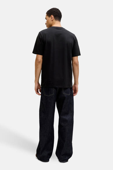 Zwart T-shirt met korte mouwen van JACK & JONES, gedragen met een wijde donkerblauwe jeans.