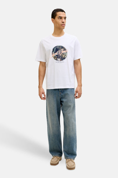 T-shirt à manches courtes blanc de JACK & JONES avec un imprimé tropical, porté avec un jean ample et des chaussures bateau.