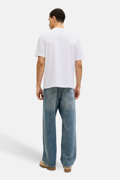 T-shirt à manches courtes blanc de JACK & JONES, porté avec un jean ample bleu délavé et des chaussures marron clair.
