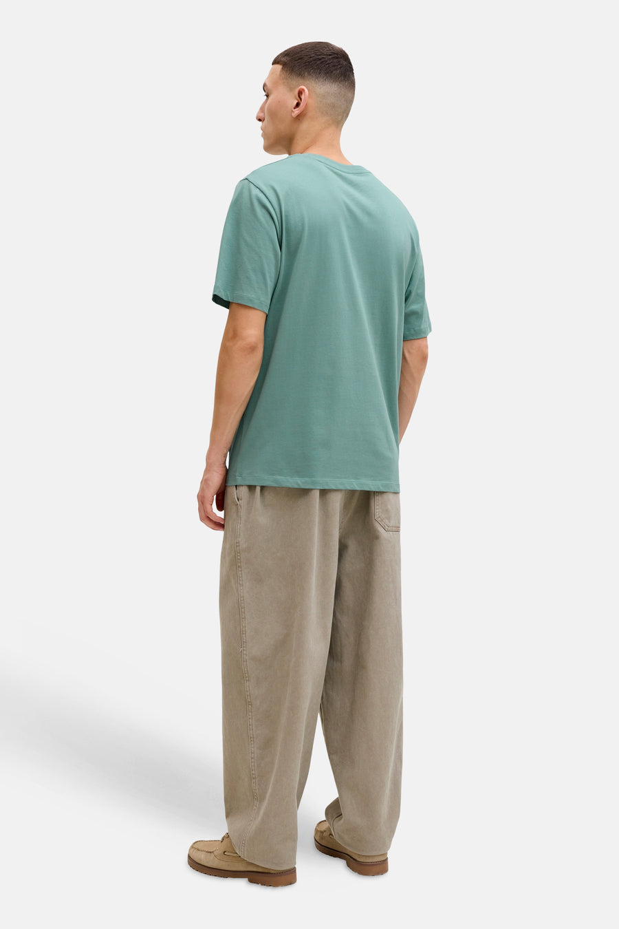 T-shirt à manches courtes bleu de JACK & JONES, porté avec un pantalon ample et des mocassins, vue de dos.
