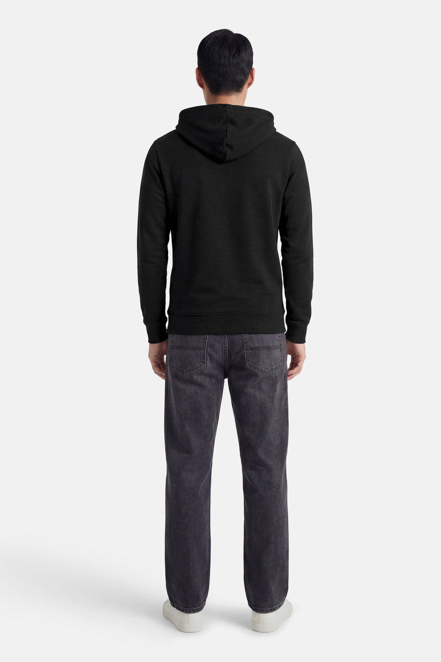 Zwarte hoodie van JACK & JONES, van achteren gezien, gedragen met een grijze jeans en witte sneakers.