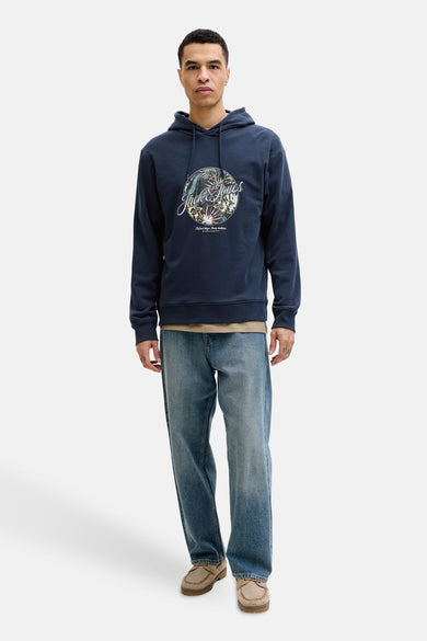 Sweat à capuche bleu de Jack & Jones, avec motif imprimé sur le devant, porté avec un jean décontracté.