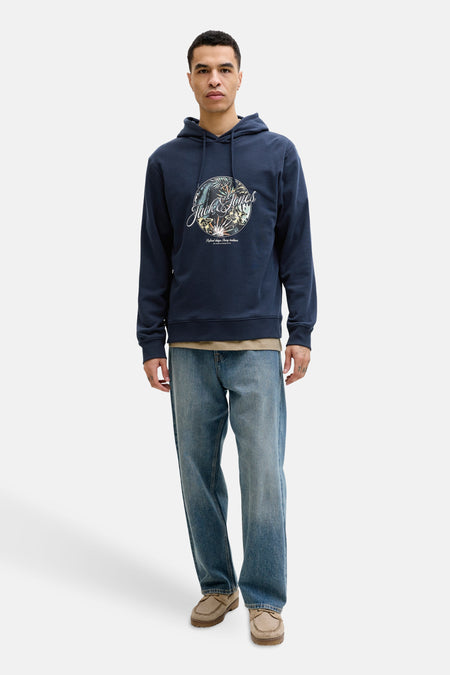 Sweat à capuche bleu de Jack & Jones, avec motif imprimé sur le devant, porté avec un jean décontracté.