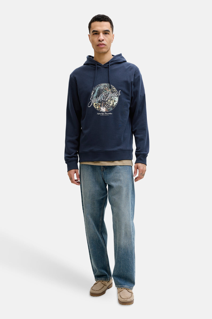 Sweat à capuche bleu de Jack & Jones, avec motif imprimé sur le devant, porté avec un jean décontracté.