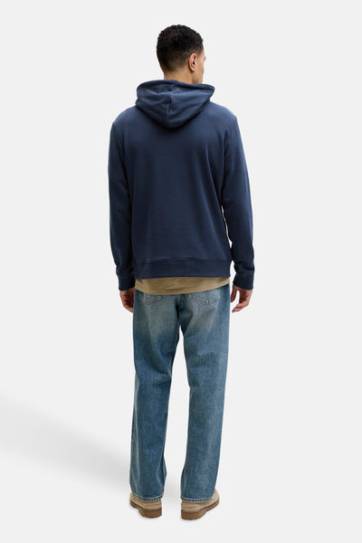 Blauwe hoodie van JACK & JONES, gedragen met een beige T-shirt en een blauwe jeans, van achteren gezien.