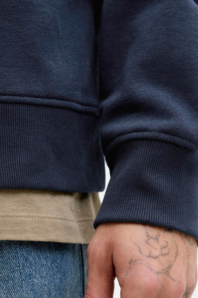 Sweat à capuche bleu de JACK & JONES avec des détails côtelés et un aperçu d'un jean bleu.
